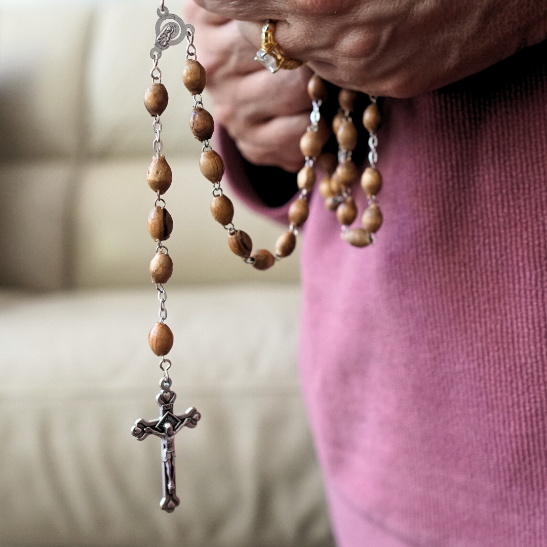 Woman praying rosary with Olive Wood rosary