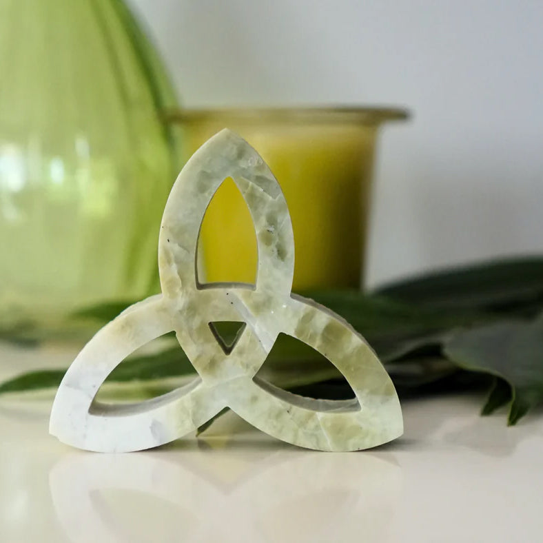 Trinity knot made from green Irish marble on table with vase and candle