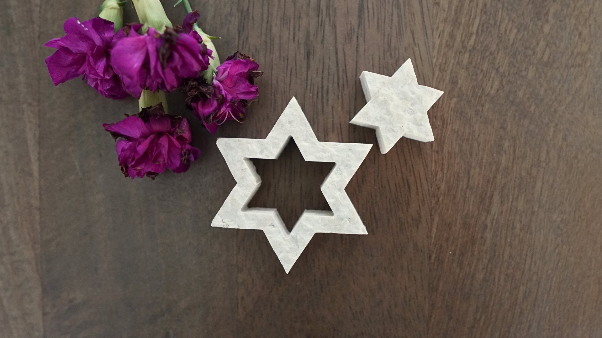 Star of David nesting stones on table with purple flowers