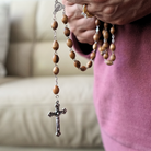Woman holding Olive Wood rosary with wooden beads