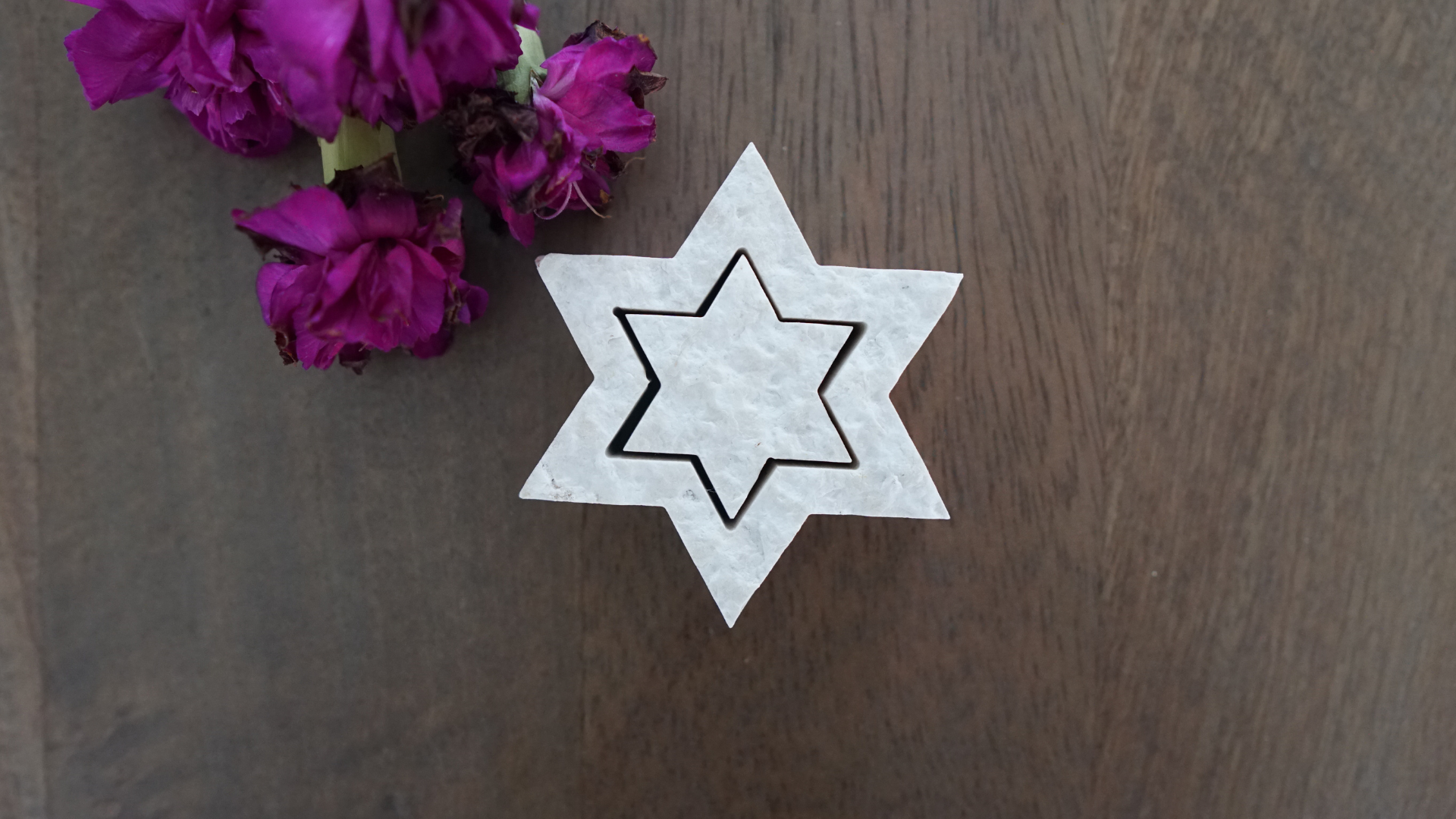 Two piece Star of David made from Jerusalem stone on table with flowers